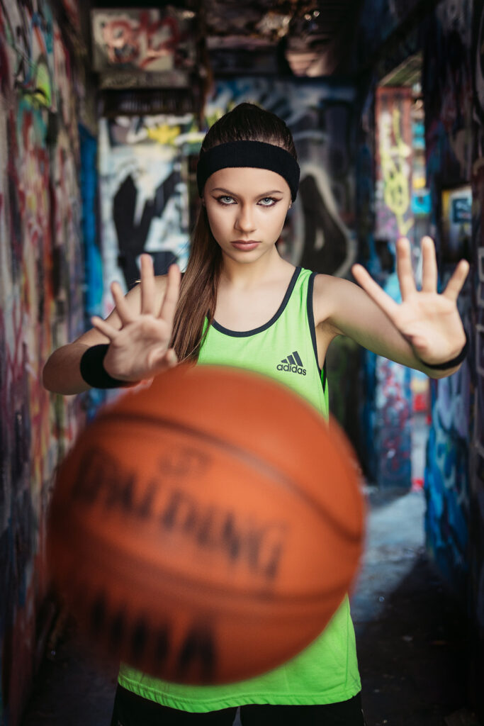 high school senior portrait session in athleisure throwing basketball at camera